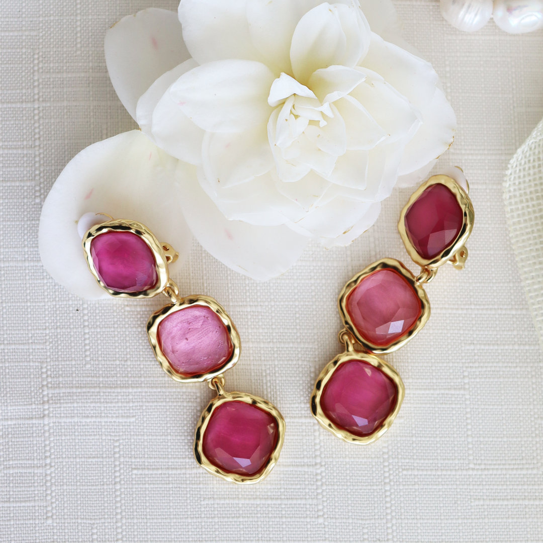 Peony Pink Bezel Trio Clip-On Earrings displayed beside white flower on neutral fabric