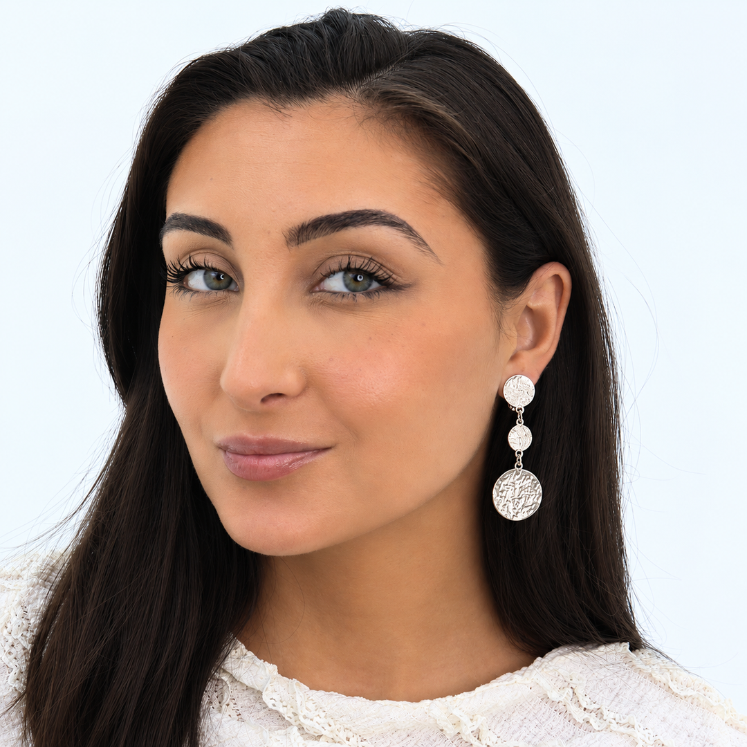 Silver Coin Trio Clip-On Earring worn on brunette model showing three dangling textured discs