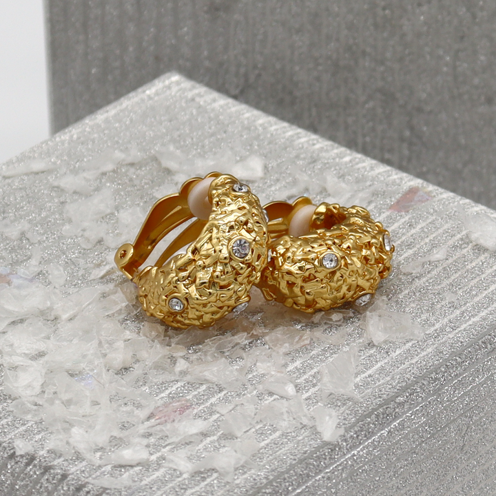 Crystal Nest Clip-On Earrings displayed on silver surface showing textured gold and crystal accents