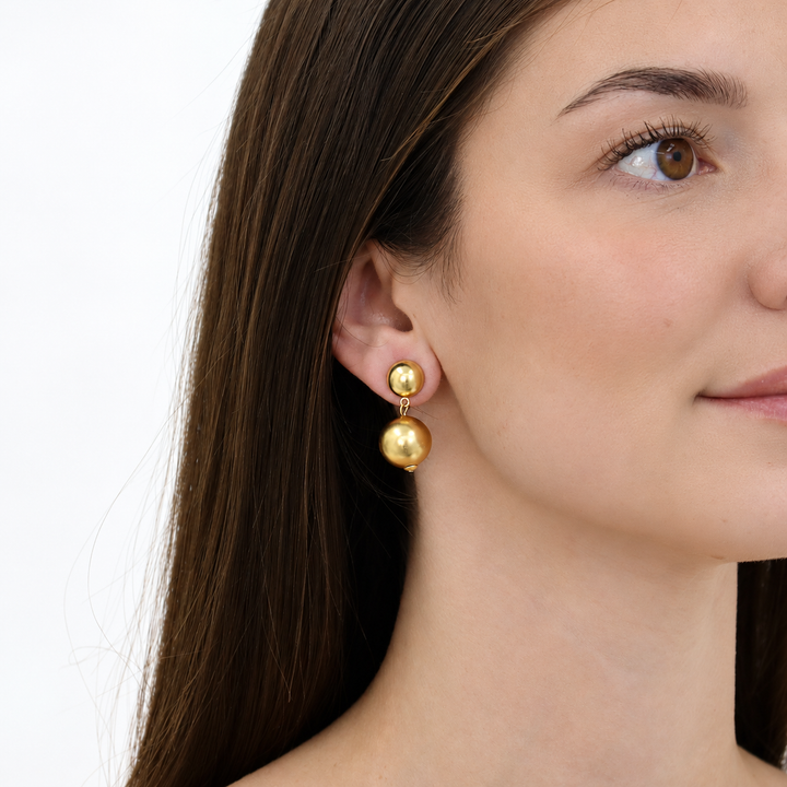 Golden Sphere Drop Earring worn on brunette model showing two dangling gold plated beads