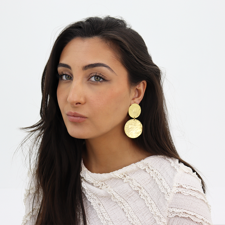 Gold Hammered Disc Statement Earrings worn on brunette model with white textured blouse