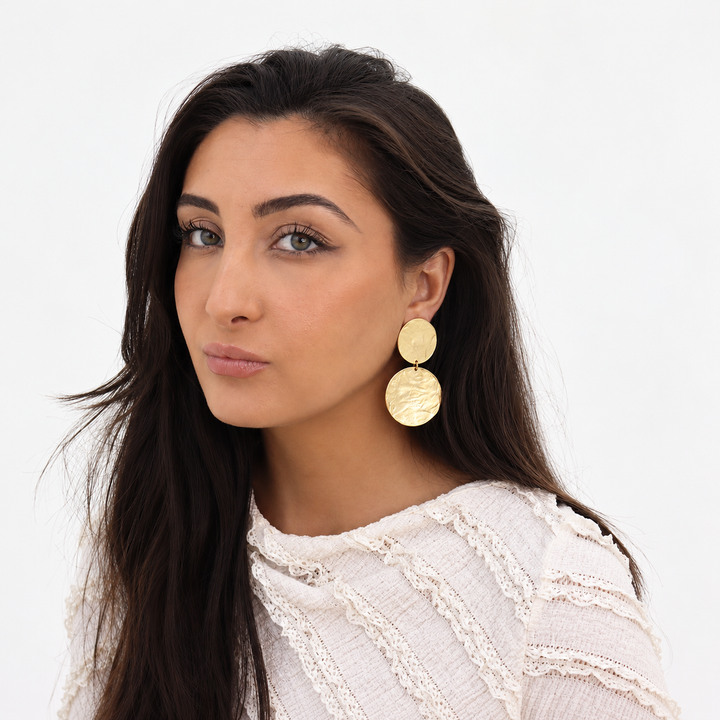Gold Hammered Discs Clip-On Earrings worn on brunette model with white textured blouse