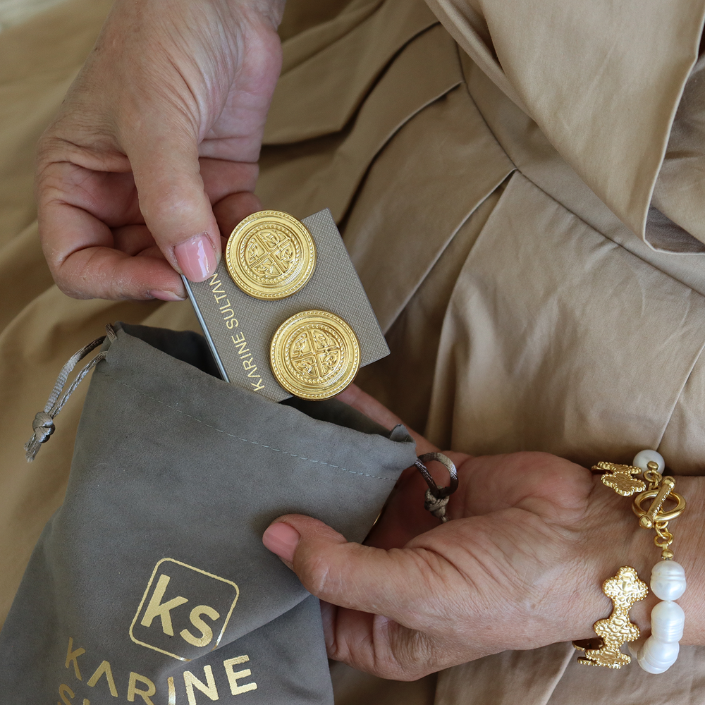 Heritage Medallion Clip-On Earrings displayed on branded jewelry card beside gray pouch