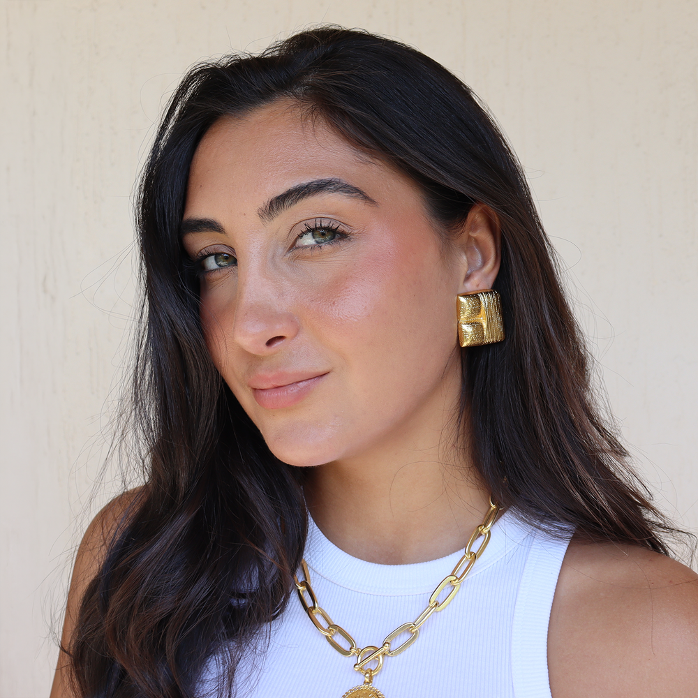 a women wearing large gold square clip-on earrings by designer karine sultan