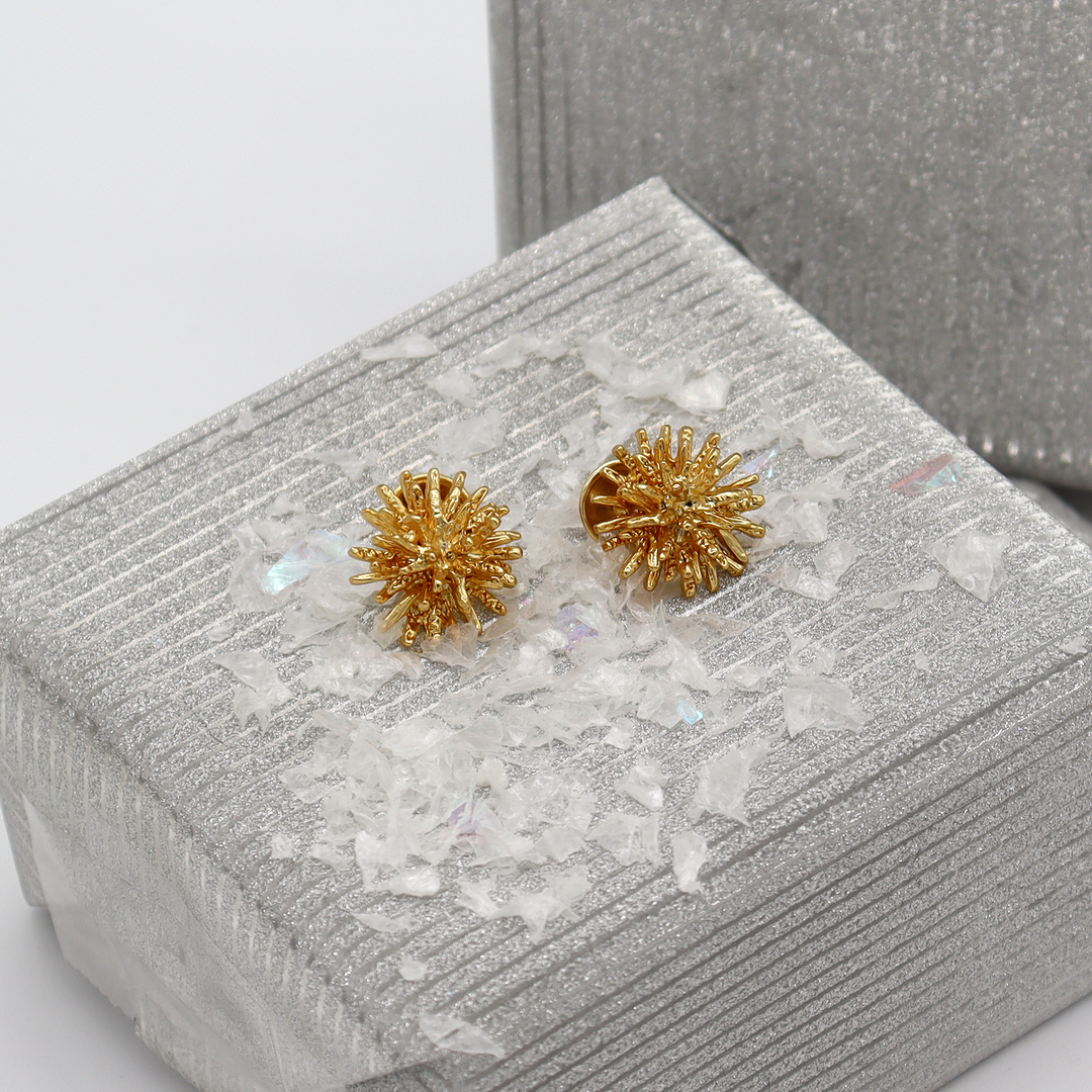 Mini Starburst Stud Earrings displayed on silver textured box with decorative white flakes