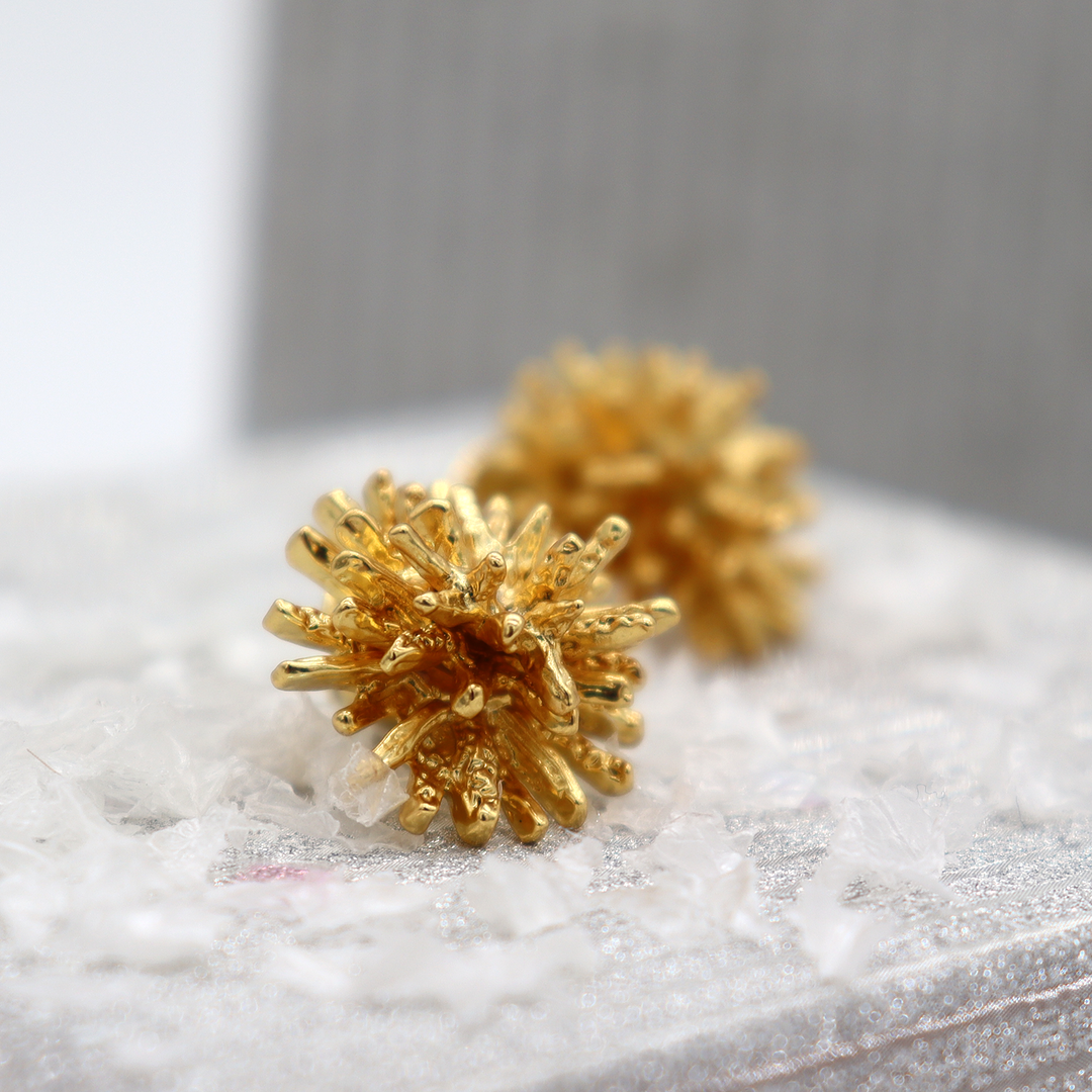 Mini Starburst Stud Earrings displayed on white fabric showing dimensional gold plated rays