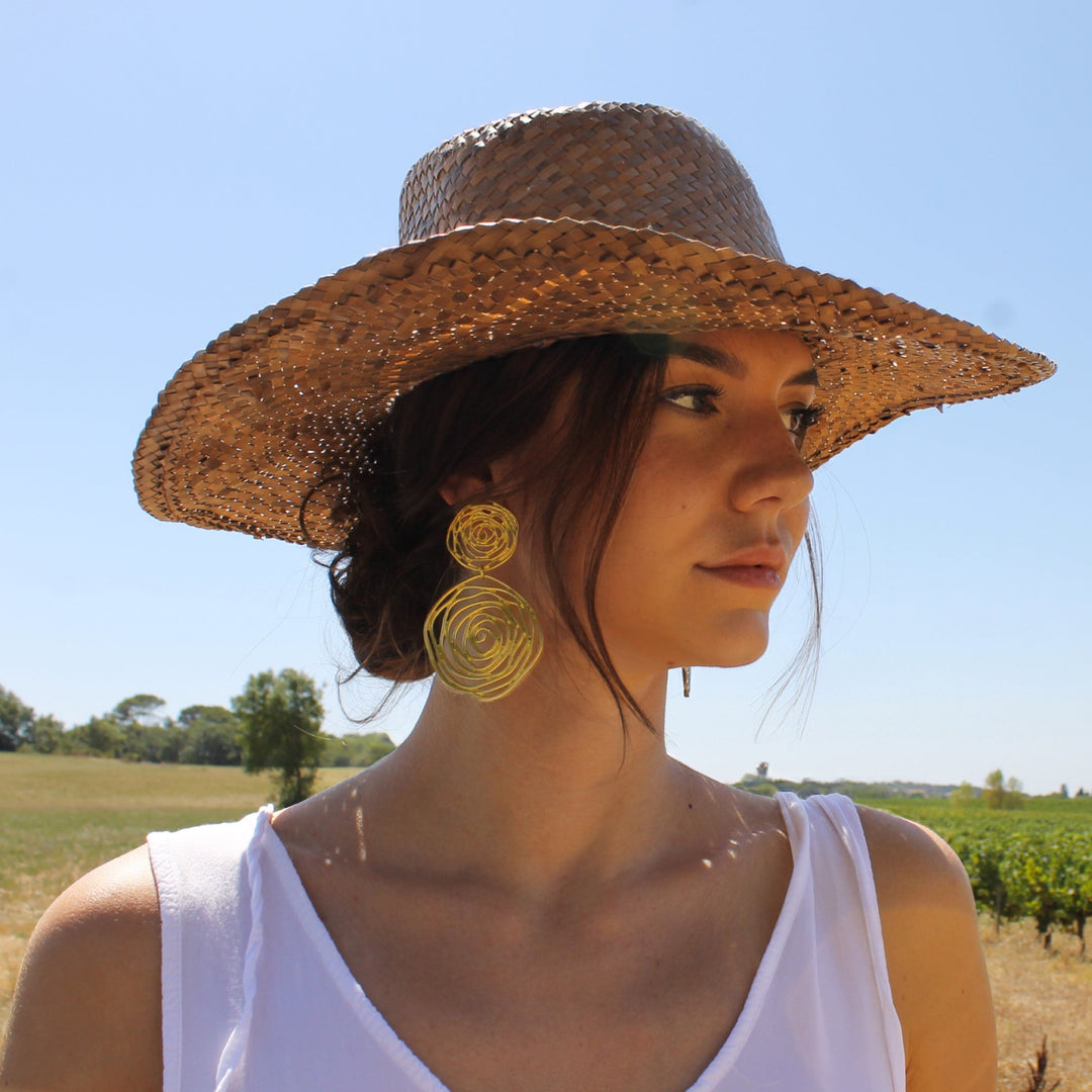 Gold Rose Cut Out Statement Earrings worn outdoors with straw hat and white top