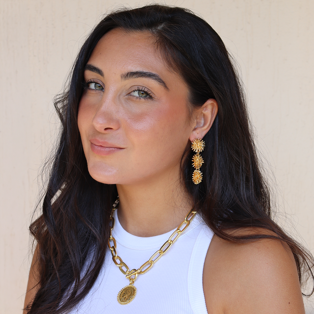 a women wearing statement three stars drop earrings, gold plated jewelry by karine sultan